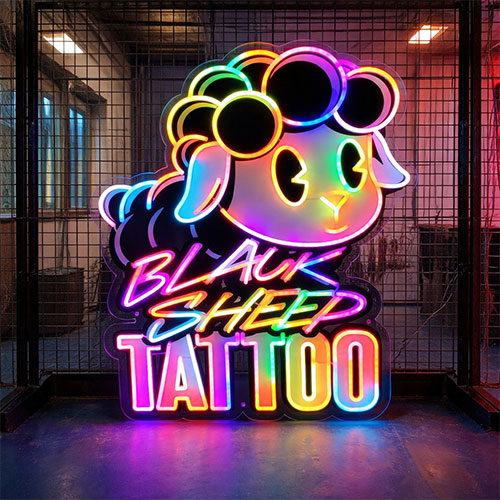 Neon sign with cartoon sheep design and 'Black Sheep Tattoo' text in a tattoo parlor setting.