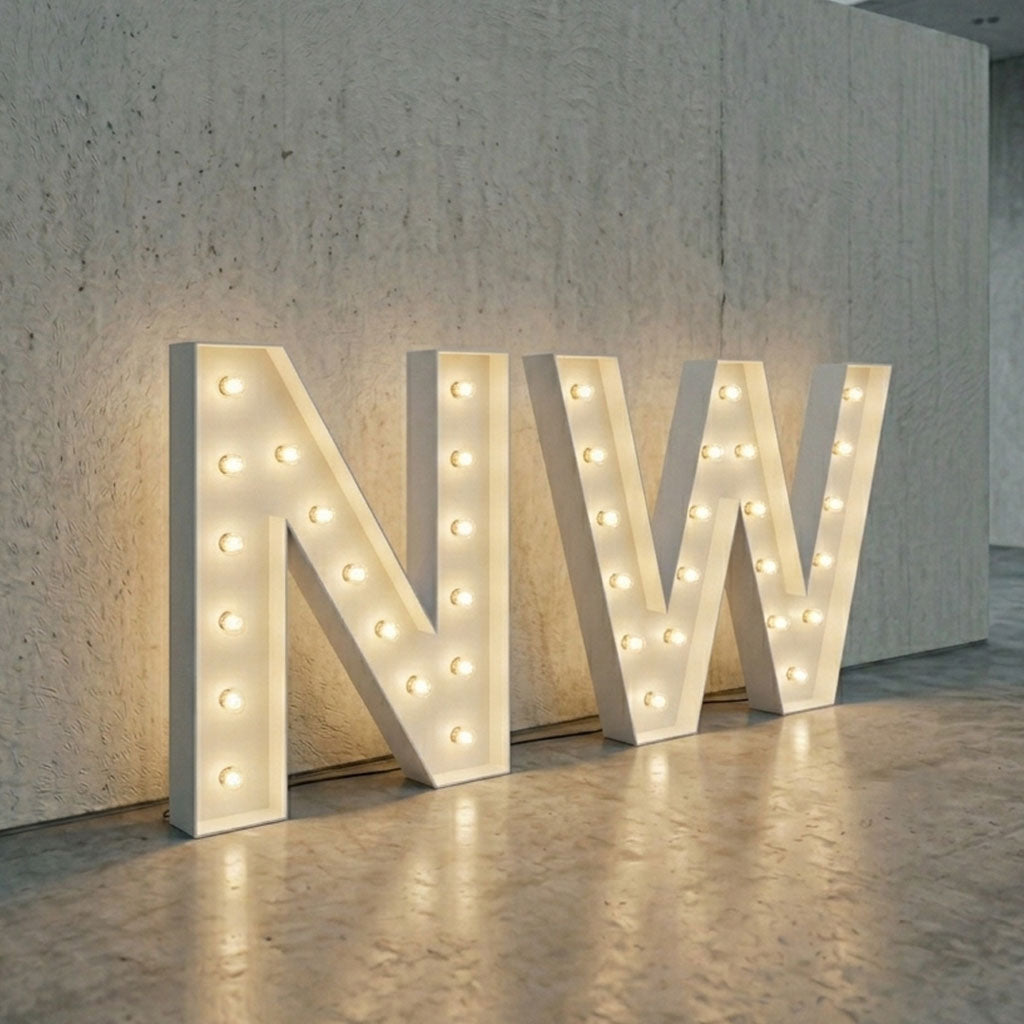 Light up letters 'NW' with lights on a concrete floor and wall background